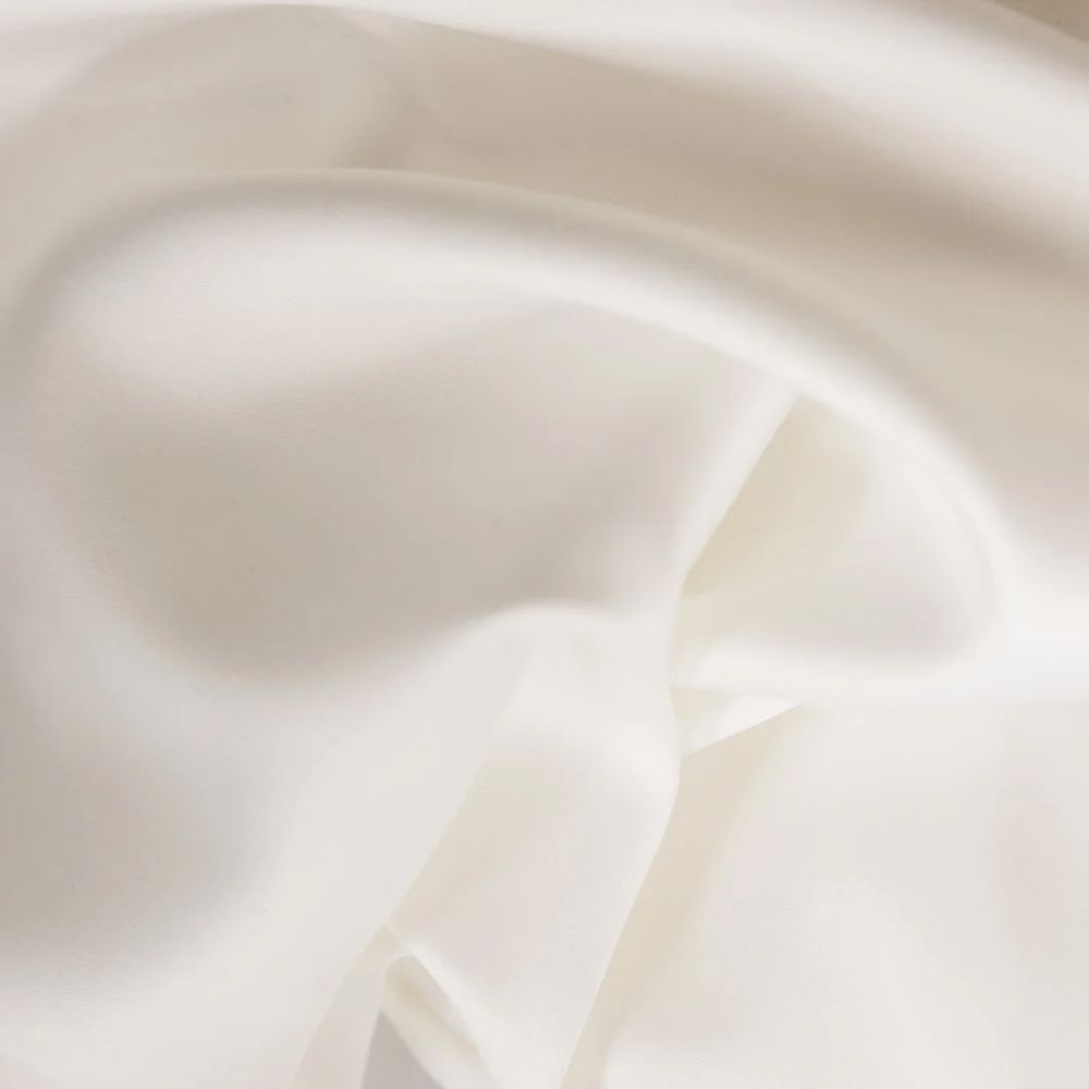 Gros plan sur du satin blanc. Tissu avec surface lisse et brillante. Plis et reflets de lumière.