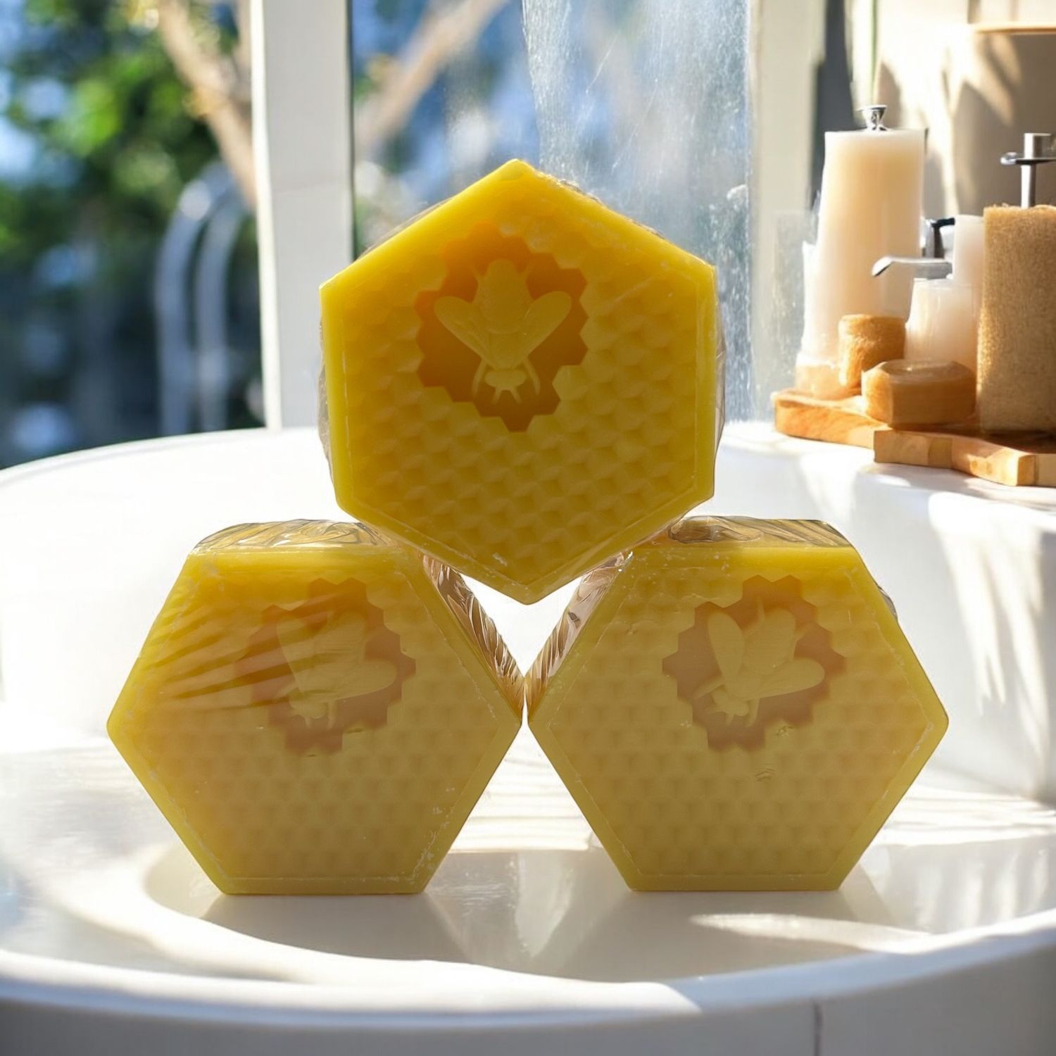 Drei sechseckige Seifenstücke in Wabenform. Jedes Stück hat ein Bienenmotiv. Die Seifen sind in Folie verpackt.