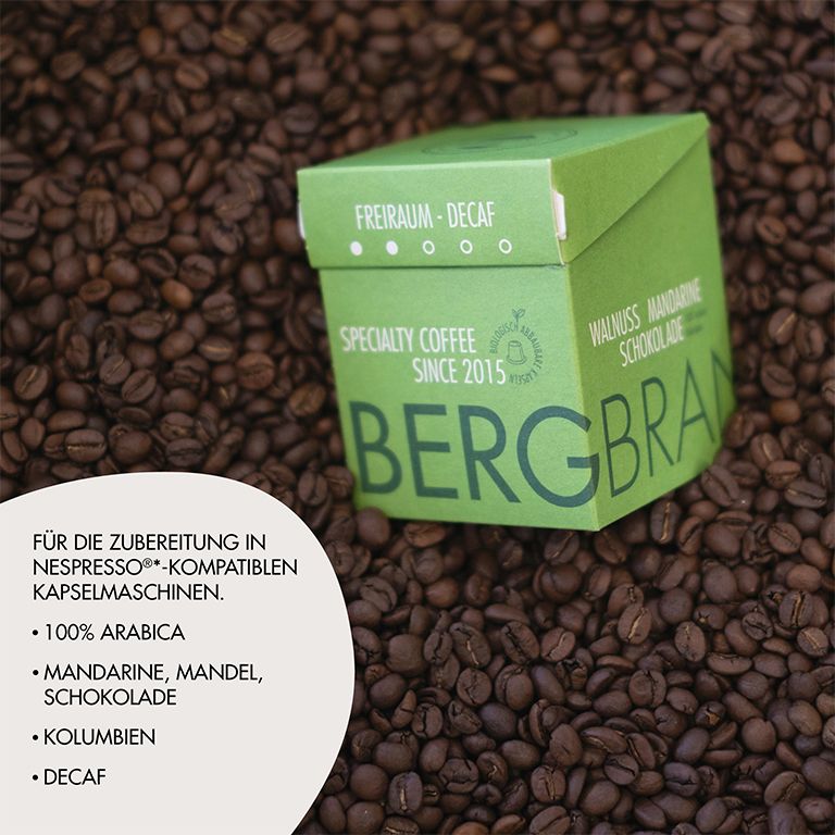 Grüne Verpackung mit BERGBRAND-Logo auf Kaffeebohnen. Text: Freiraum-Decaf, Specialty Coffee, Walnuss Mandarine Schokolade. Weitere Texte.