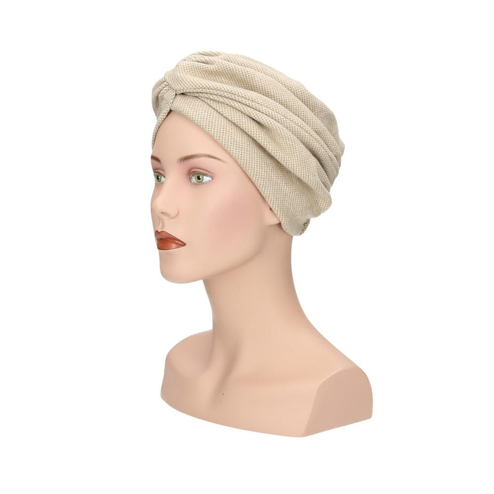 Beigefarbener Turban aus Stoff mit Knoten vorne, auf einer Schaufensterpuppe.