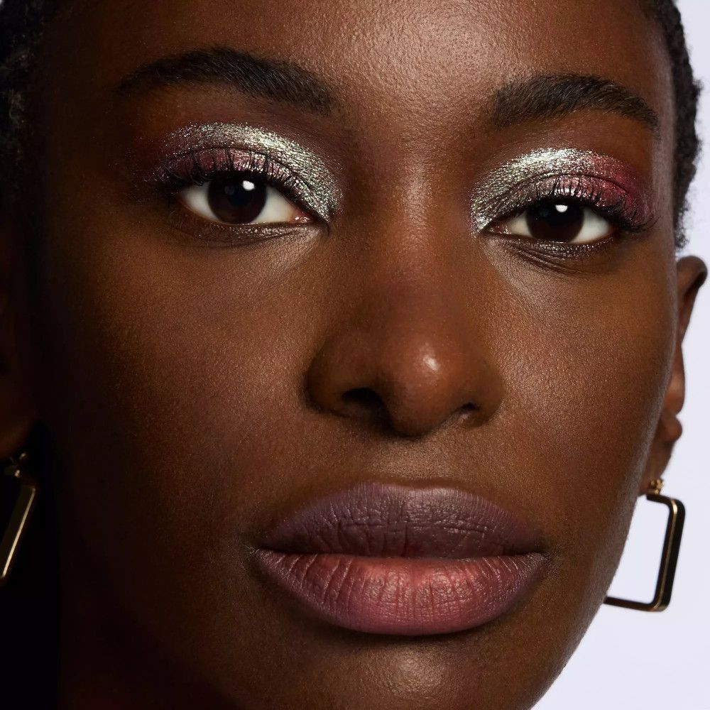 Nahaufnahme eines Gesichts mit aufgetragenem Lidschatten in Silber, Rosa und Lila.