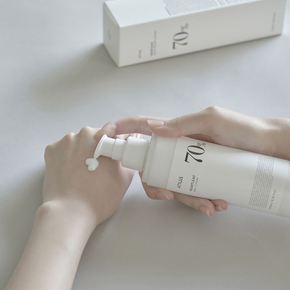 Eine Hand drückt eine weiße Lotion aus einer Flasche auf die andere Hand.