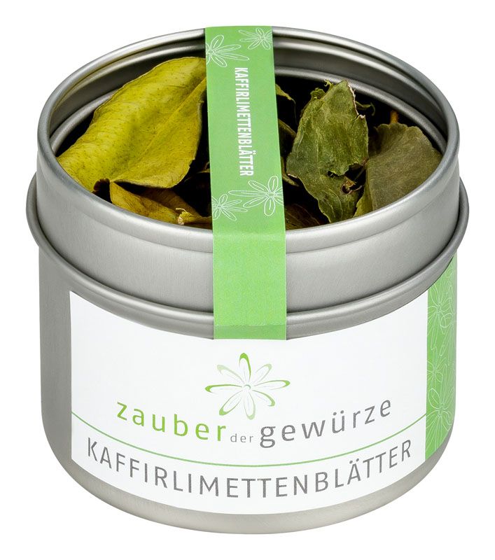 Runde Dose mit Kaffirlimettenblättern. Aufkleber mit Schriftzug: Zauber der Gewürze, Kaffirlimettenblätter. Grünes Band mit Schriftzug.