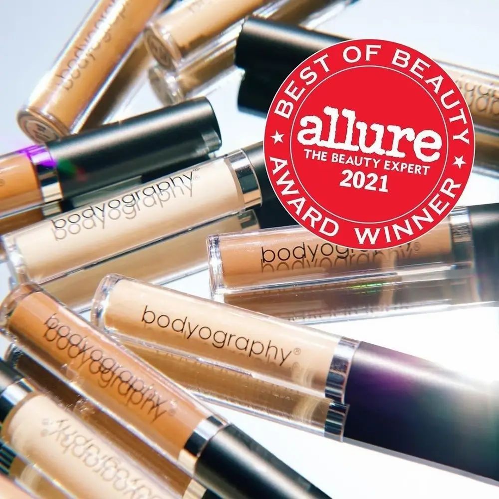 Mehrere Concealer-Tuben auf einer spiegelnden Oberfläche. Ein roter Aufkleber mit der Aufschrift "Best of Beauty" und "Allure" ist sichtbar.