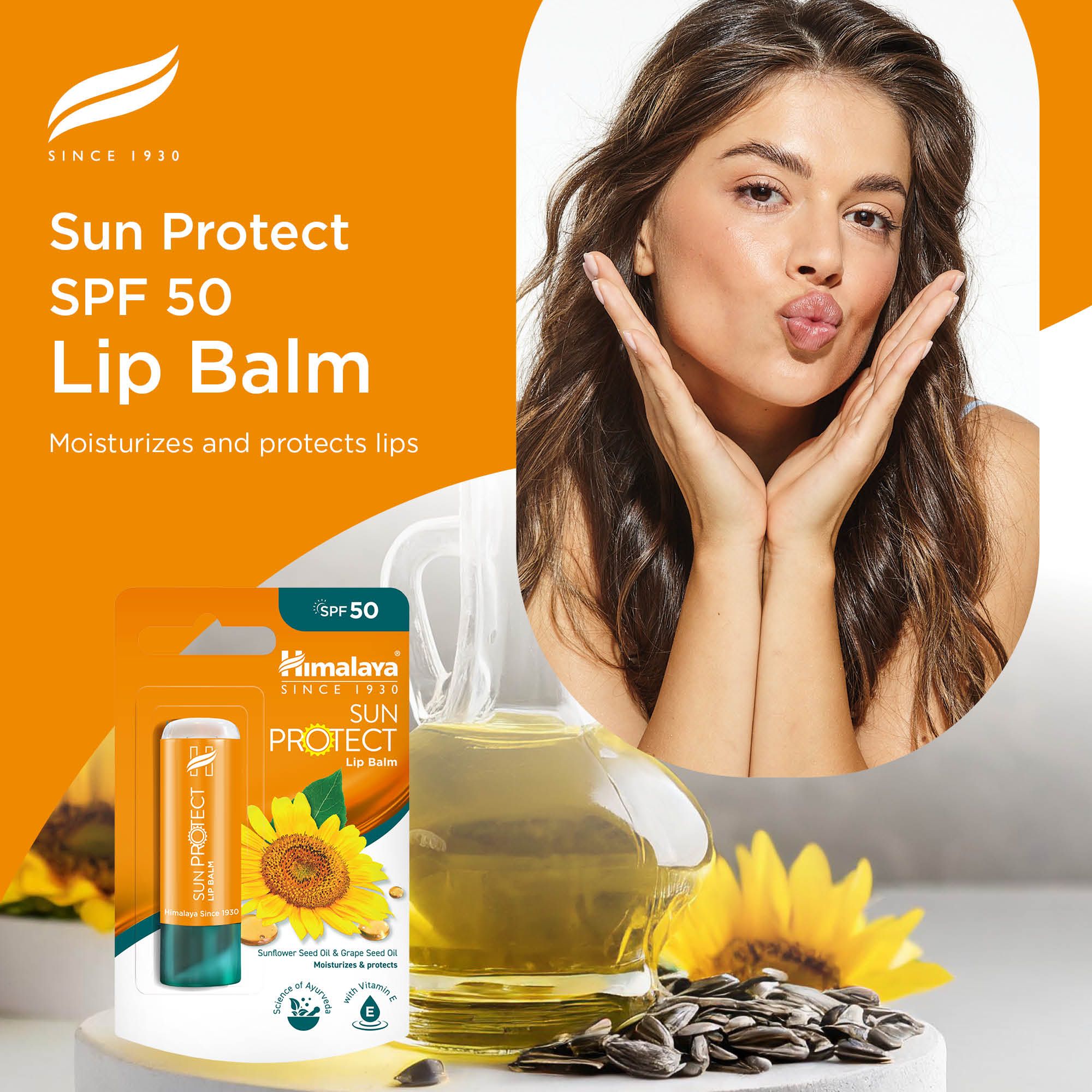 Himalaya Sun Protect Lippenbalsam SPF 50 in Verpackung, daneben ein Glas Öl und Sonnenblumen.