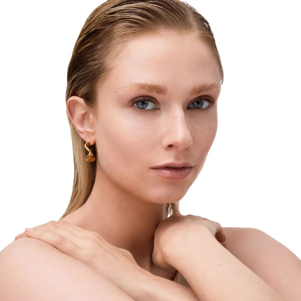 Porträt einer Frau mit blonden Haaren und goldenen Ohrringen. Hautton und Gesichtszüge deutlich erkennbar.