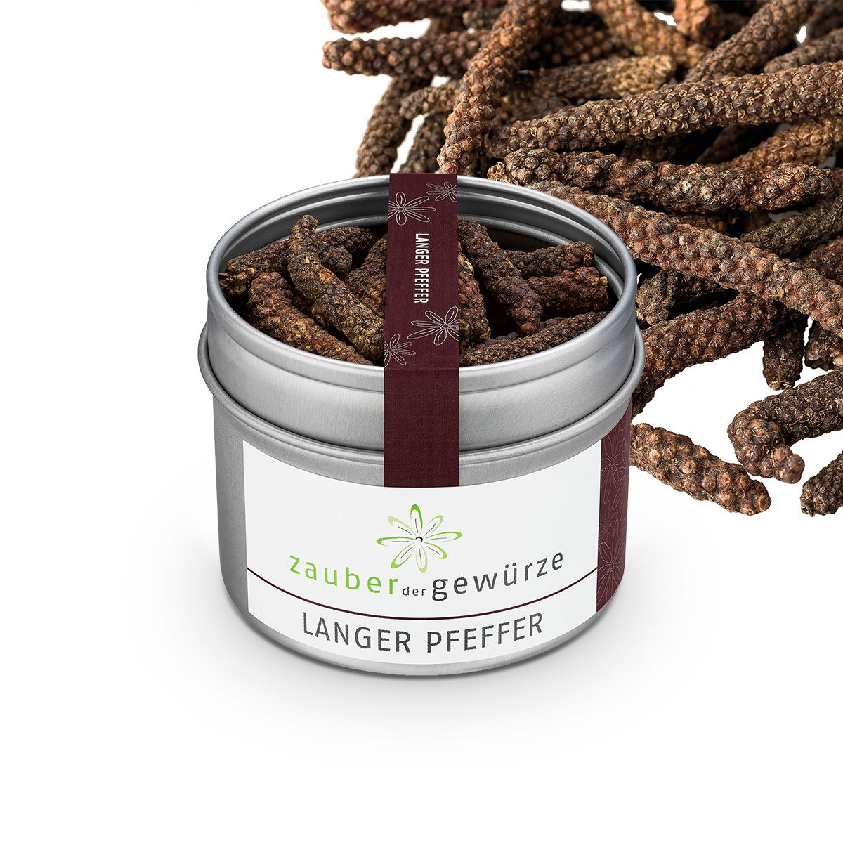 Zylindrische Dose mit "Zauber der Gewürze Langer Pfeffer". Pfefferkörner liegen daneben. Aufkleber mit Logo.