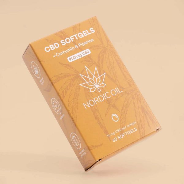 Schräg gestellte Verpackung mit CBD Softgels. Aufschrift: CBD Softgels + Curcumin & Piperin, 960mg CBD, Nordic Oil. Gelbe Verpackung.