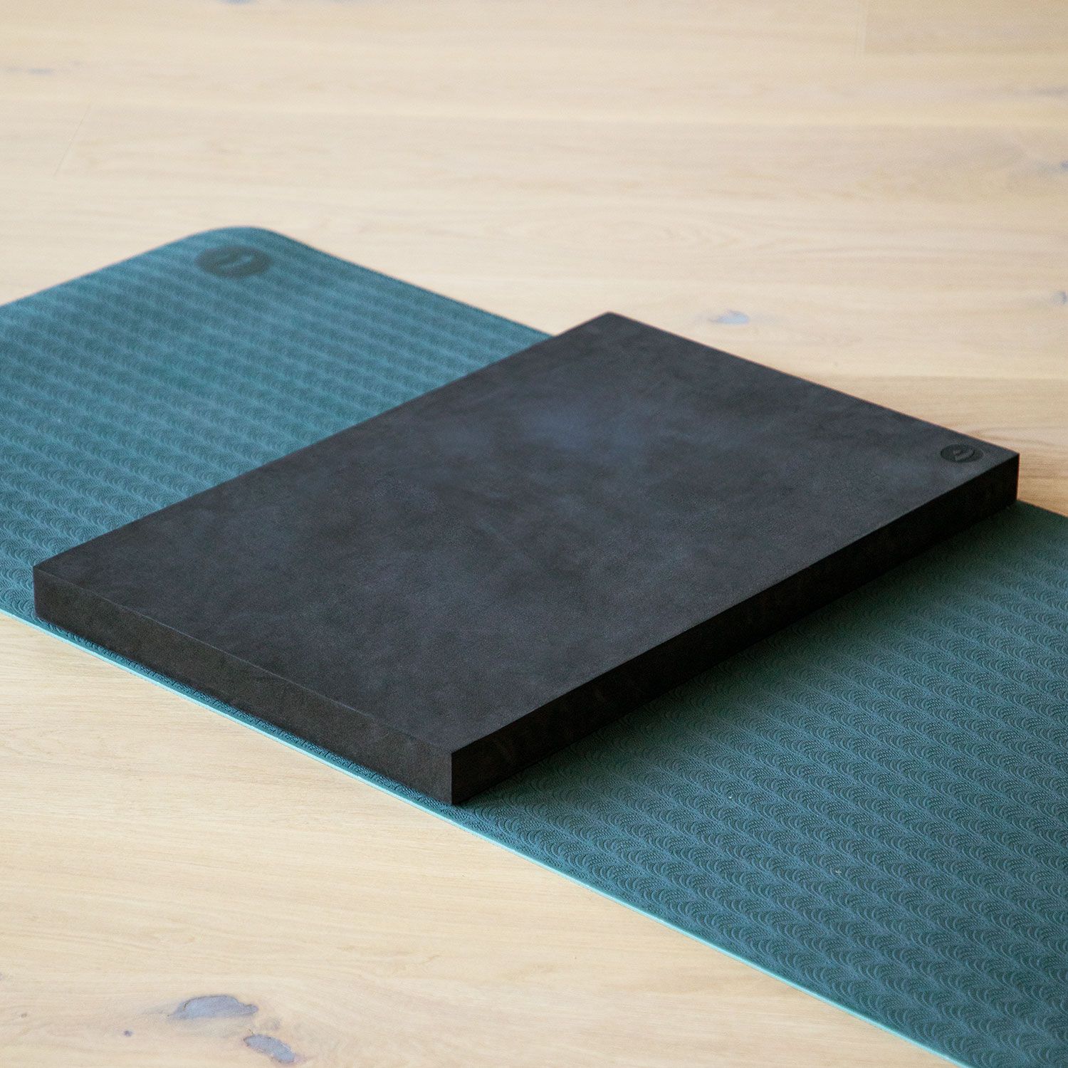 Schwarzer Yoga-Block XL auf grüner Yogamatte. Rechteckige Form. Logo auf dem Block.