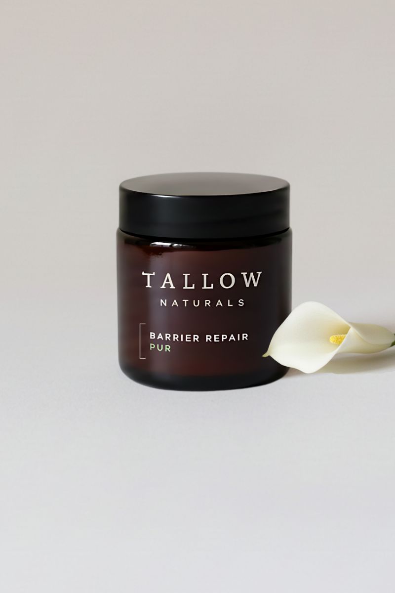 Braune Dose mit schwarzem Deckel. Aufschrift: Tallow Naturals, Barrier Repair Pur. Daneben eine weiße Blüte.