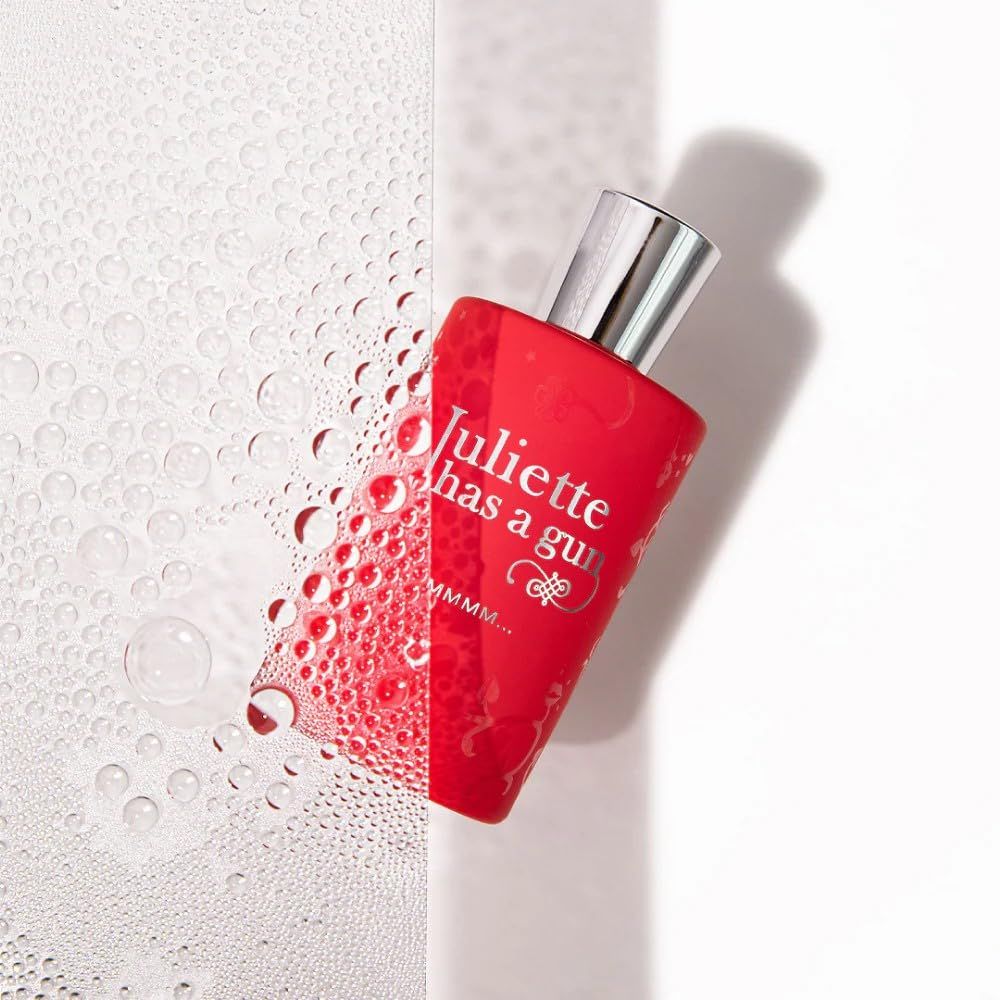 Rote Parfumflasche mit silbernem Deckel, teilweise mit Wassertropfen bedeckt. Aufschrift: Juliette has a gun, MMMM...