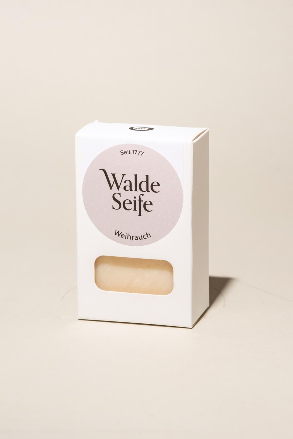 Weisse Verpackung mit rundem Etikett. Darauf steht "Walde Seife Weihrauch". Ein Seifenstück ist durch ein Fenster sichtbar.