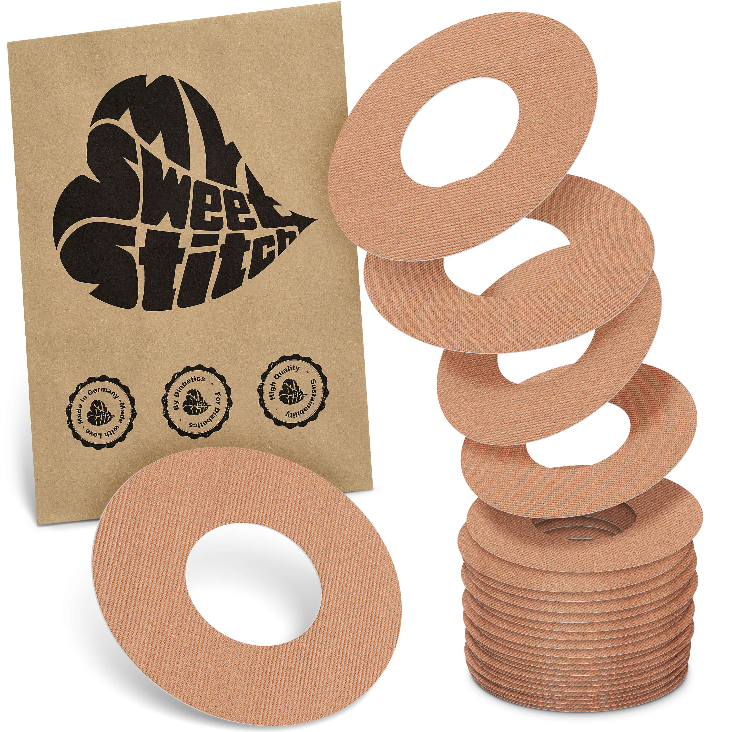 Beige Fixierringe mit Loch, neben brauner Verpackung mit Logo und Qualitätssiegeln.