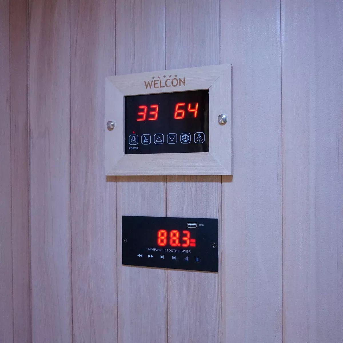 Holzpaneel mit zwei digitalen Anzeigen. Oben: WELCON-Logo. Unten: Bluetooth-Player-Anzeige. Rote Ziffern.