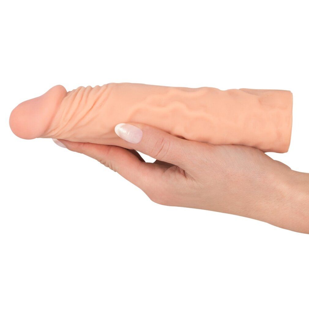 Hautfarbene Penis-Erweiterungshülse, gehalten in einer Hand. Deutlich sichtbare geriffelte Oberfläche.