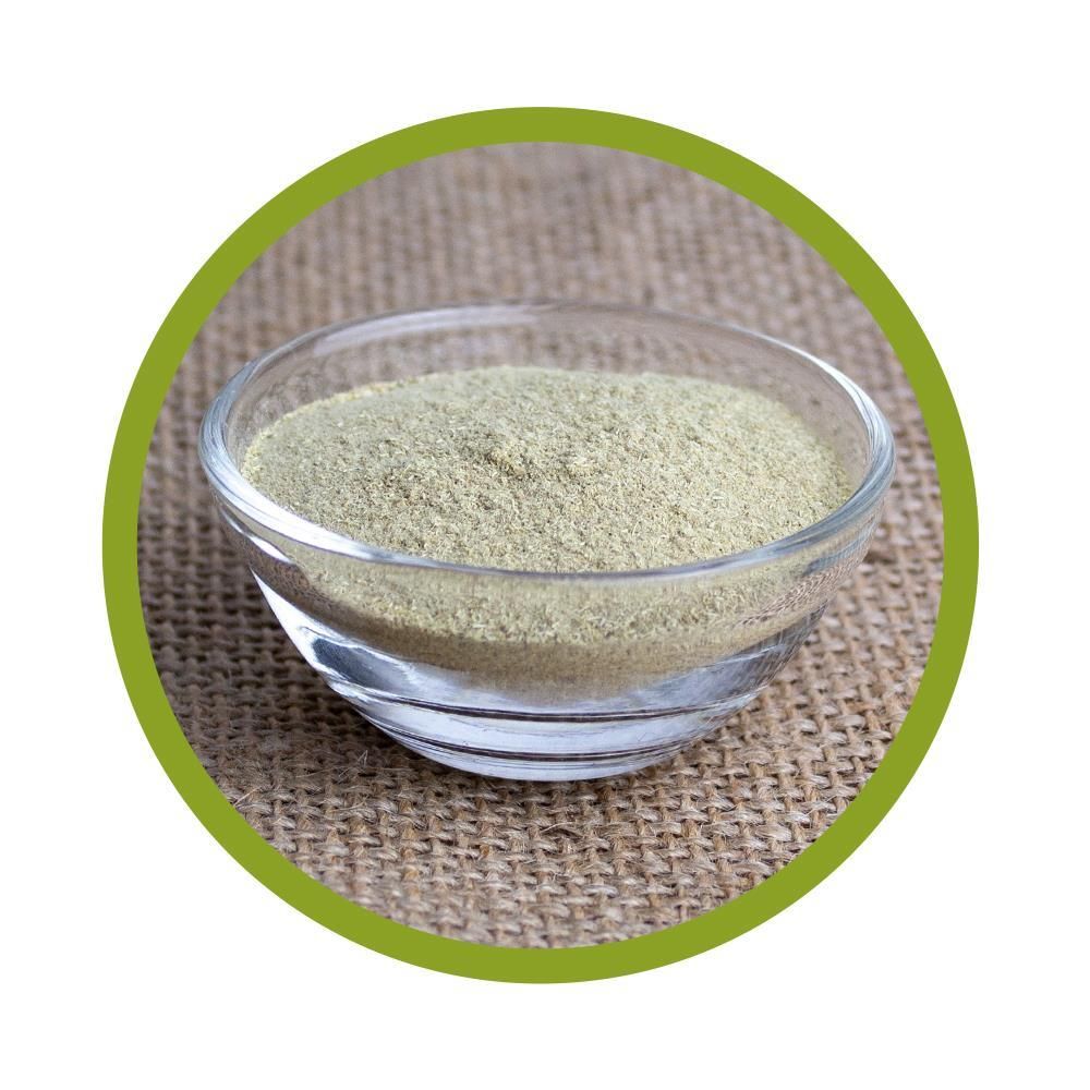 Runde Glasschale mit grünlichem Pulver. Auf grobem Untergrund.