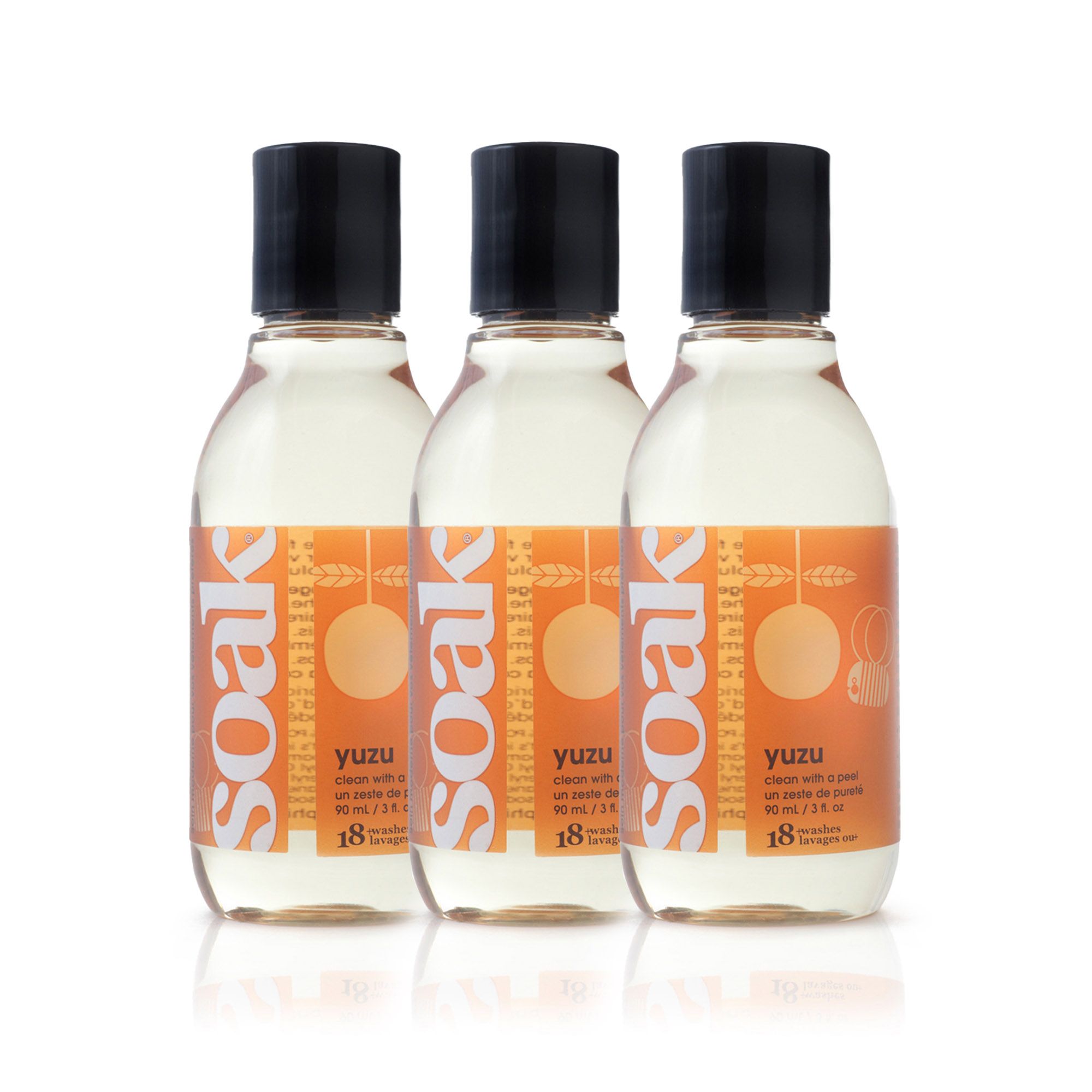 Drei Flaschen mit klarer Flüssigkeit und schwarzen Deckeln. Orangefarbene Etiketten mit Text: soak, yuzu, 18 Waschgänge.