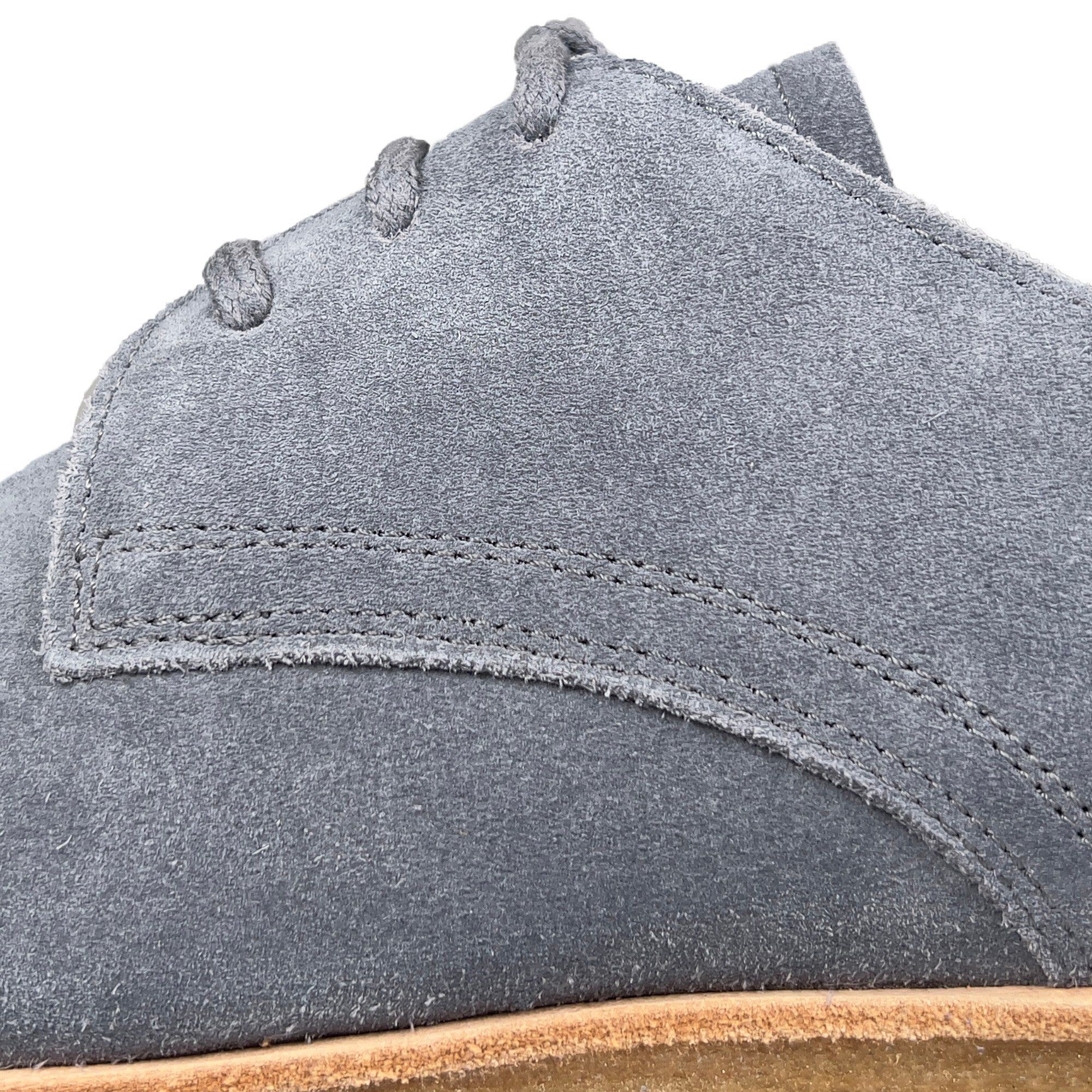 Detailaufnahme eines grauen Schnürschuhs. Wildleder. Nahtdetails.