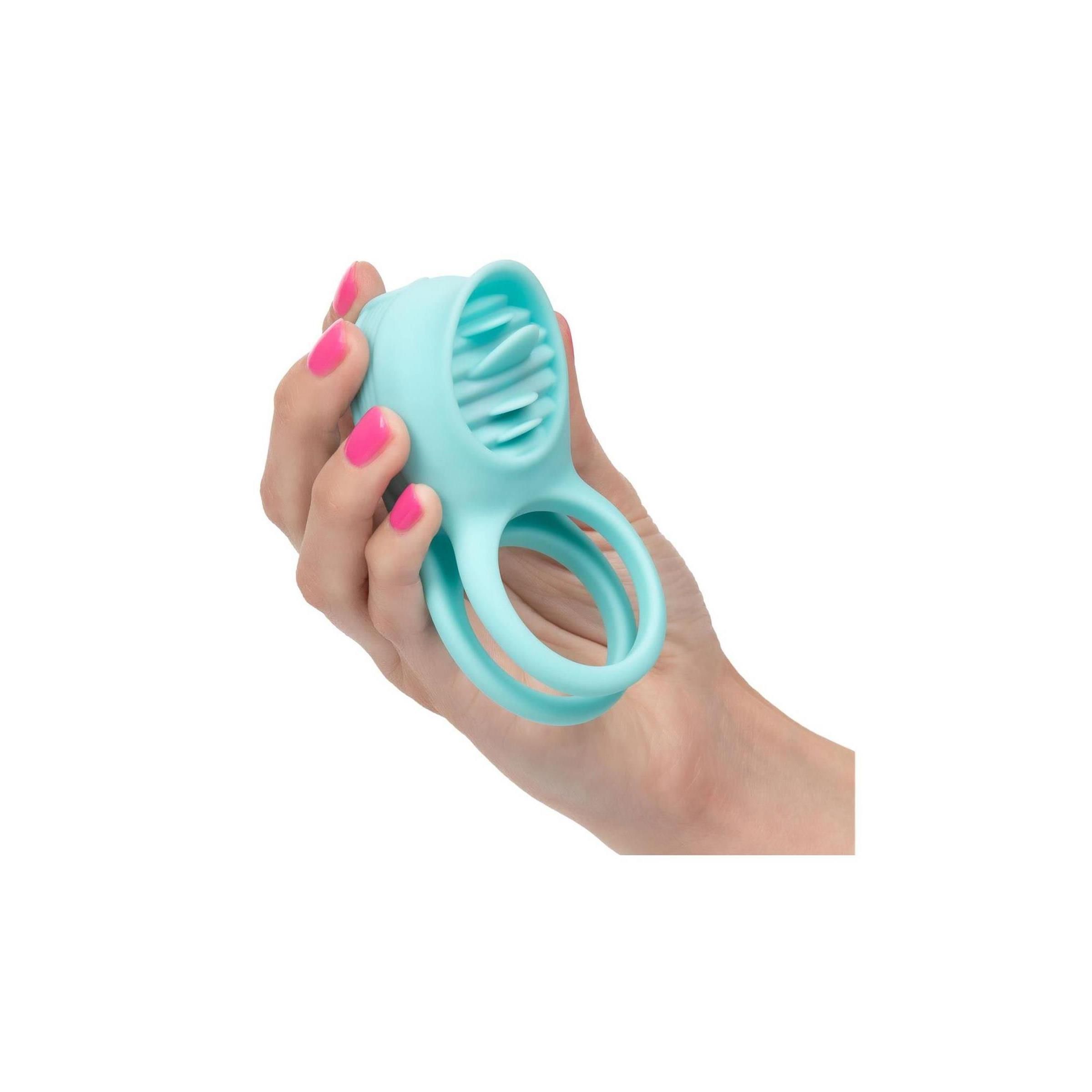 Türkisfarbener Enhancer in einer Hand gehalten. Zwei Ringe, strukturierter Kopf. Rosa lackierte Fingernägel.
