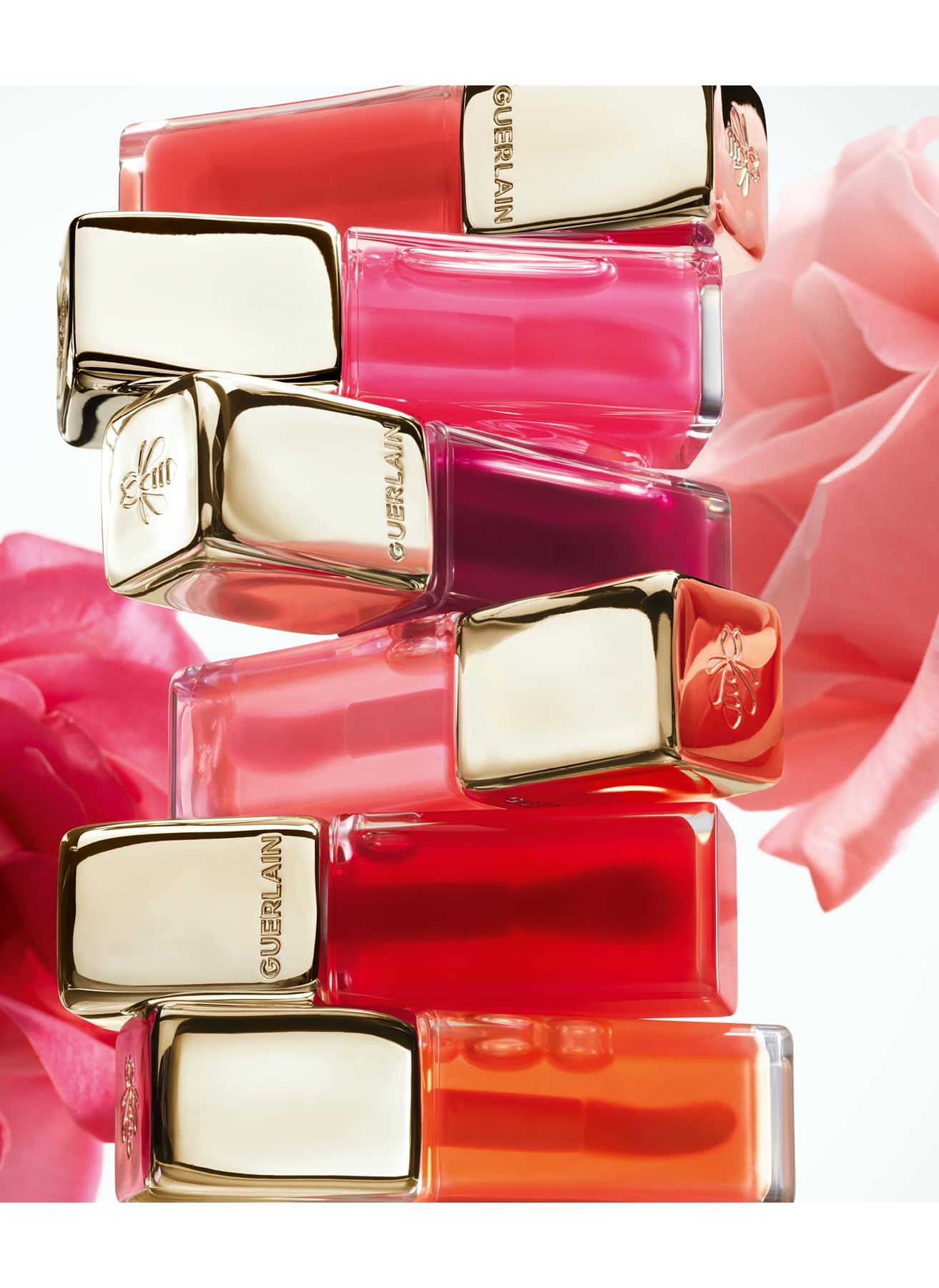 Gestapelte Lippenöl-Flakons. Goldene Kappen mit Bienen-Logo. Guerlain-Logo.