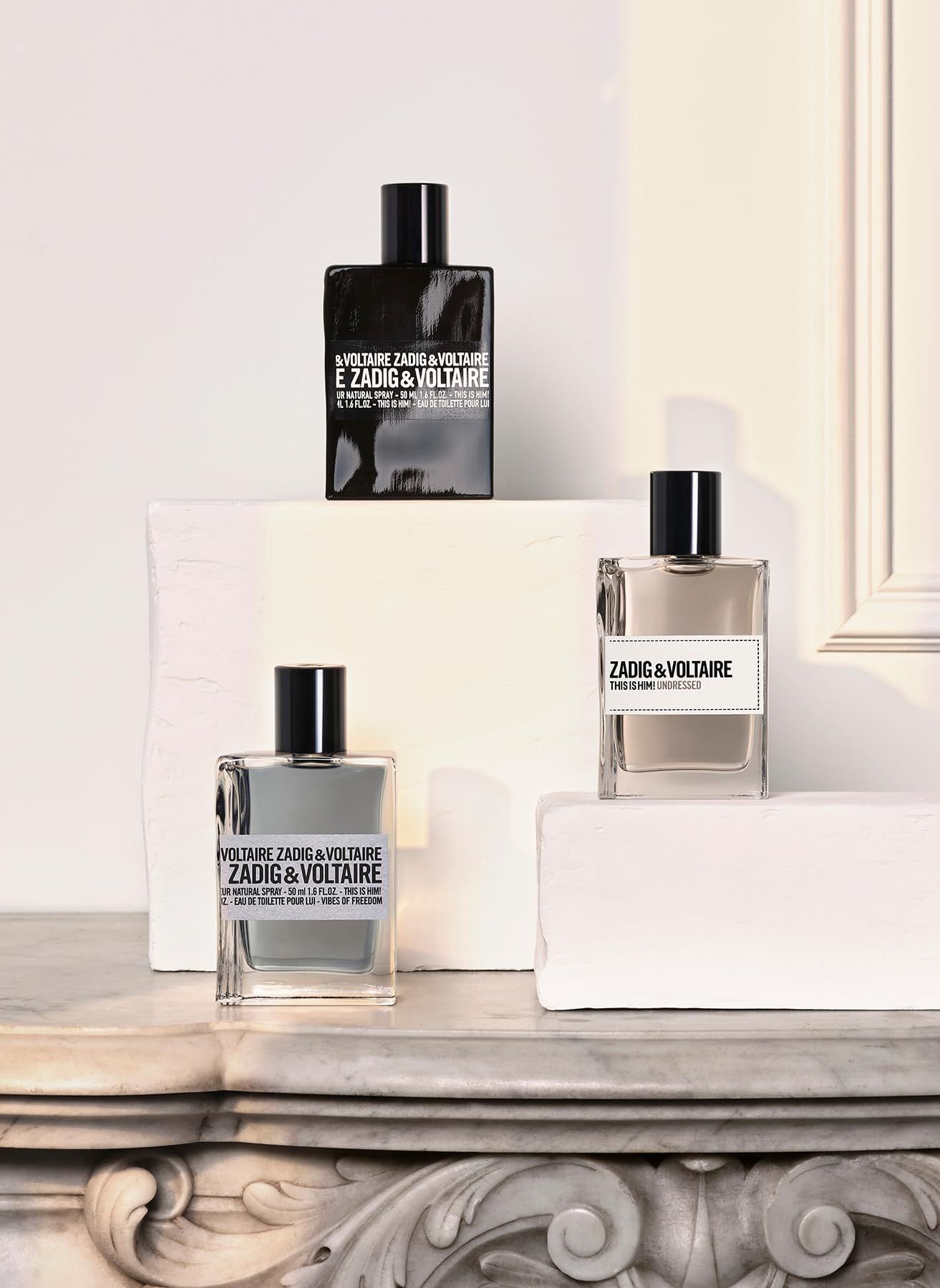 Drei Zadig & Voltaire Flakons. Schwarzer, grauer und klarer Flakon. Auf weißen Blöcken. Schwarze Verschlüsse.