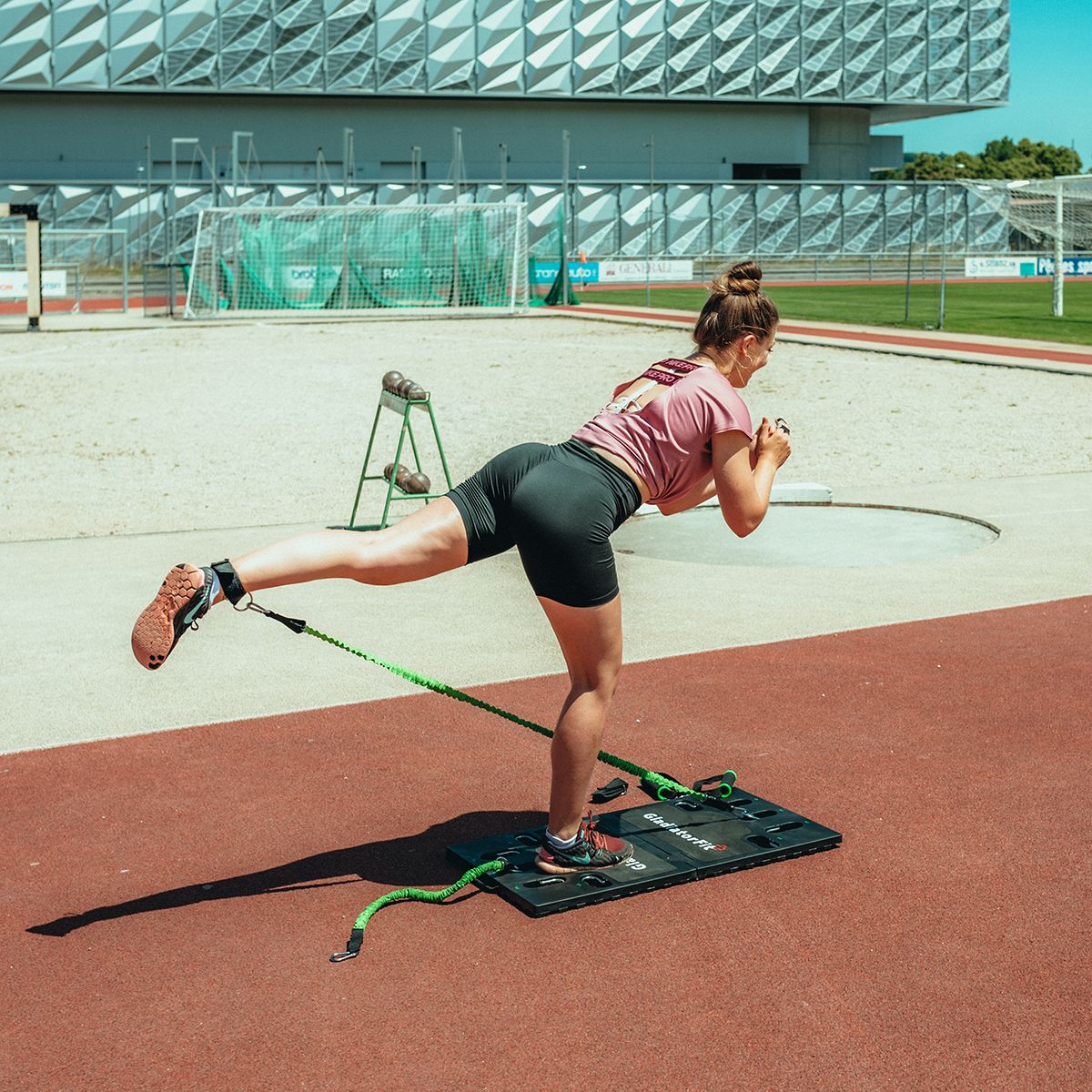 Frau trainiert auf Fitness-Board mit Widerstandsbändern. Bein gestreckt, Board mit Marke.