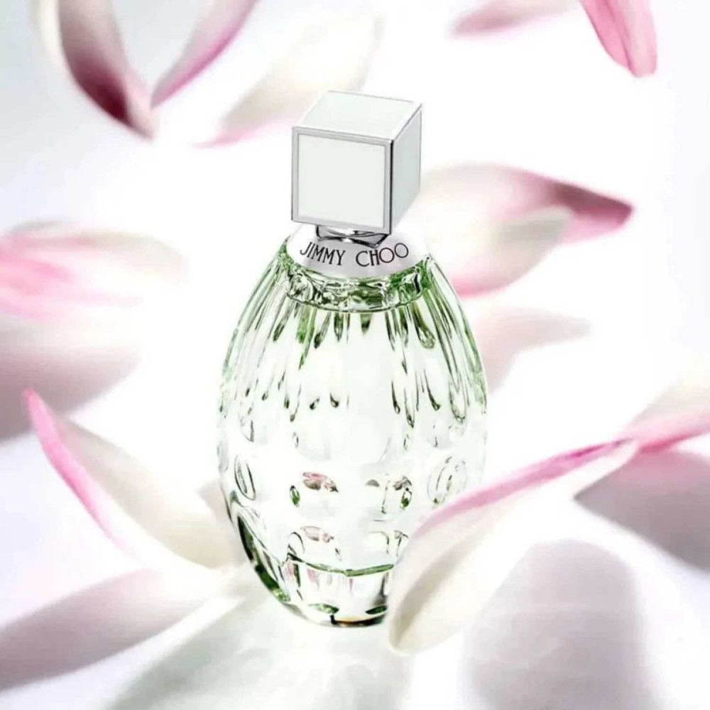 Jimmy Choo Floral Eau de Toilette Flakon. Geriffelter Flakon mit hellgrünem Verschluss. Blütenblätter im Hintergrund.