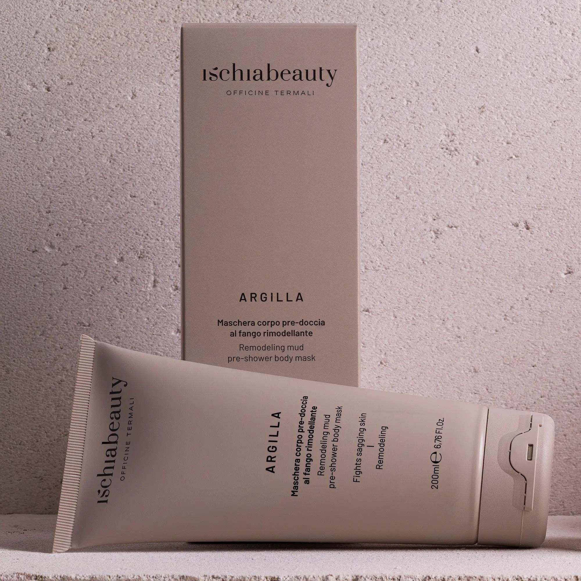 Beige Tube und Schachtel. Aufschrift: Ischiabeauty, Argilla, Maschera corpo pre-doccia al fango rimodellante. Produkt liegt.