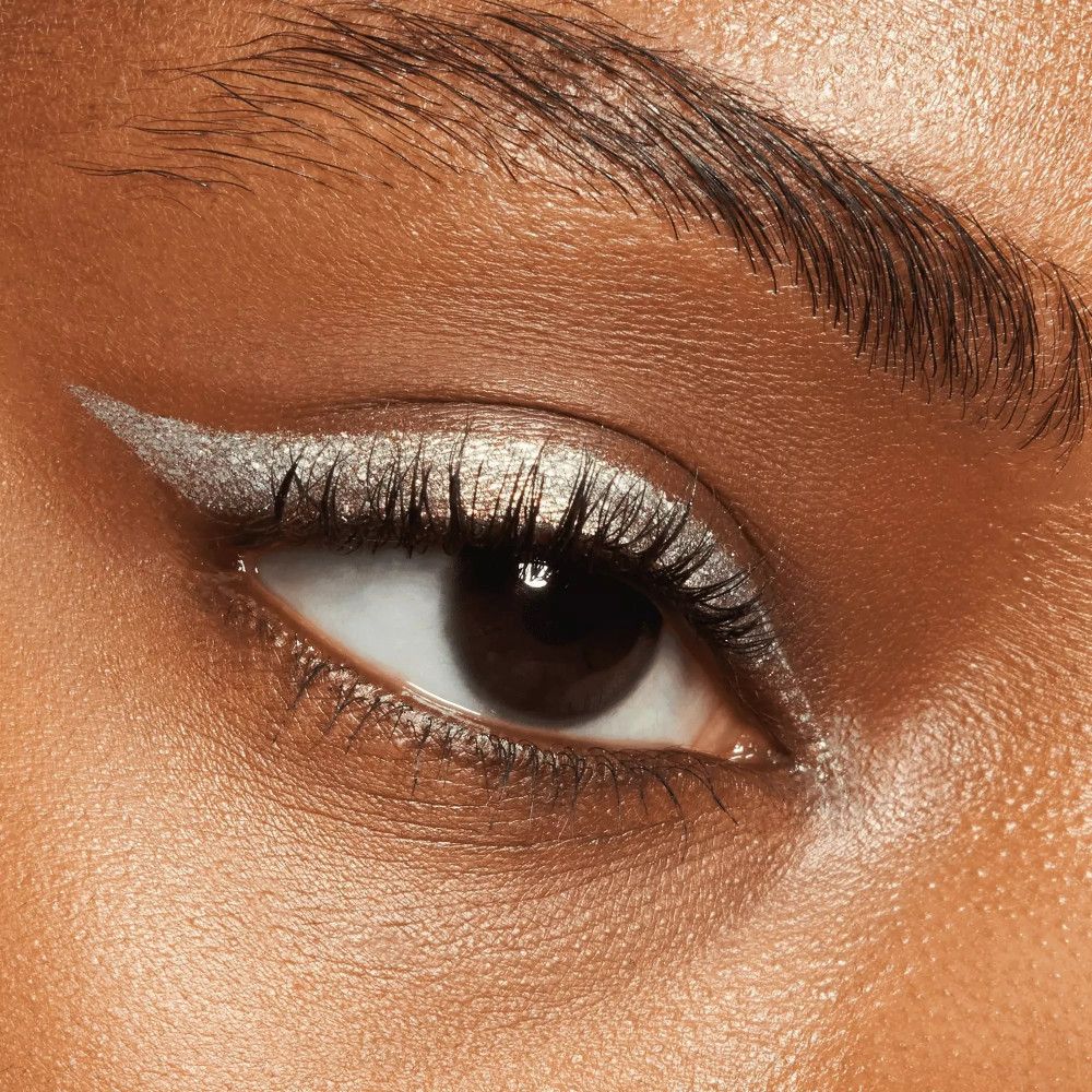 Nahaufnahme eines Auges mit silbernem Eyeliner und Lidschatten. Die Haut ist gebräunt.