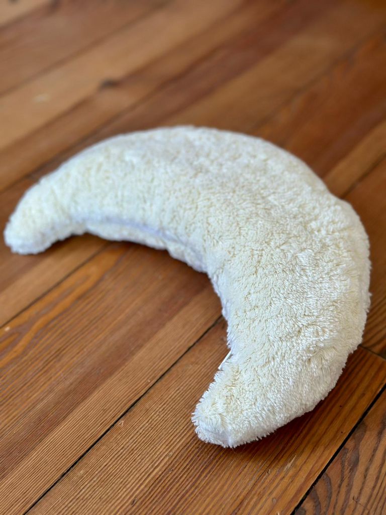 Crèmekleurige maan van zacht materiaal. Op houten ondergrond. Halvemaanvorm.