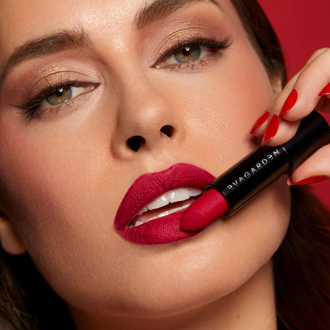 Frau mit rotem Lippenstift. Schwarze Hülse mit weißem Schriftzug. Rote Lippen.