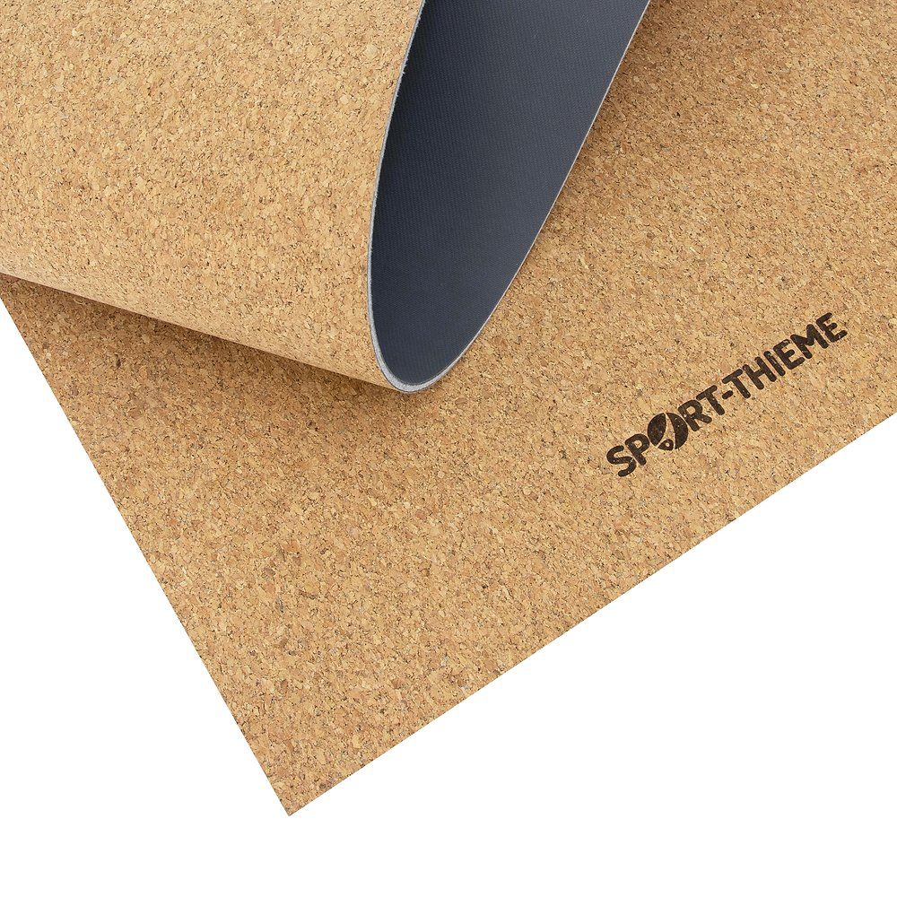 Yoga-Matte mit Kork-Oberfläche. Sport-Thieme Logo. Teilweise aufgerollt, graue Rückseite.