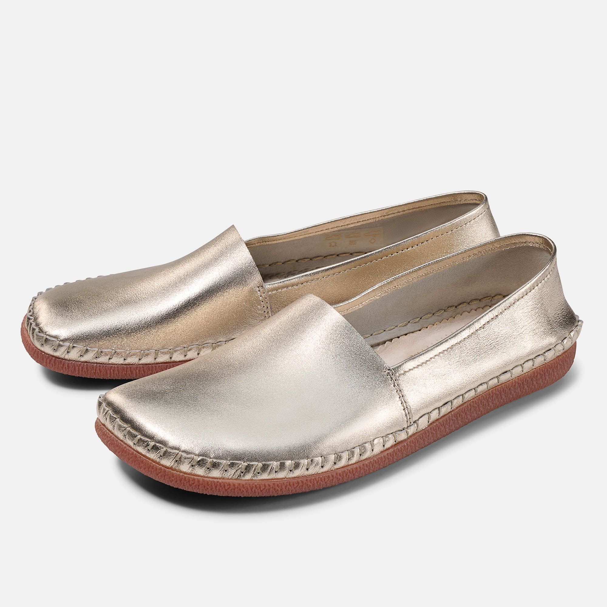 Zwei goldfarbene Slipper mit brauner Sohle. Quadratische Zehenpartie, sichtbare Nähte.