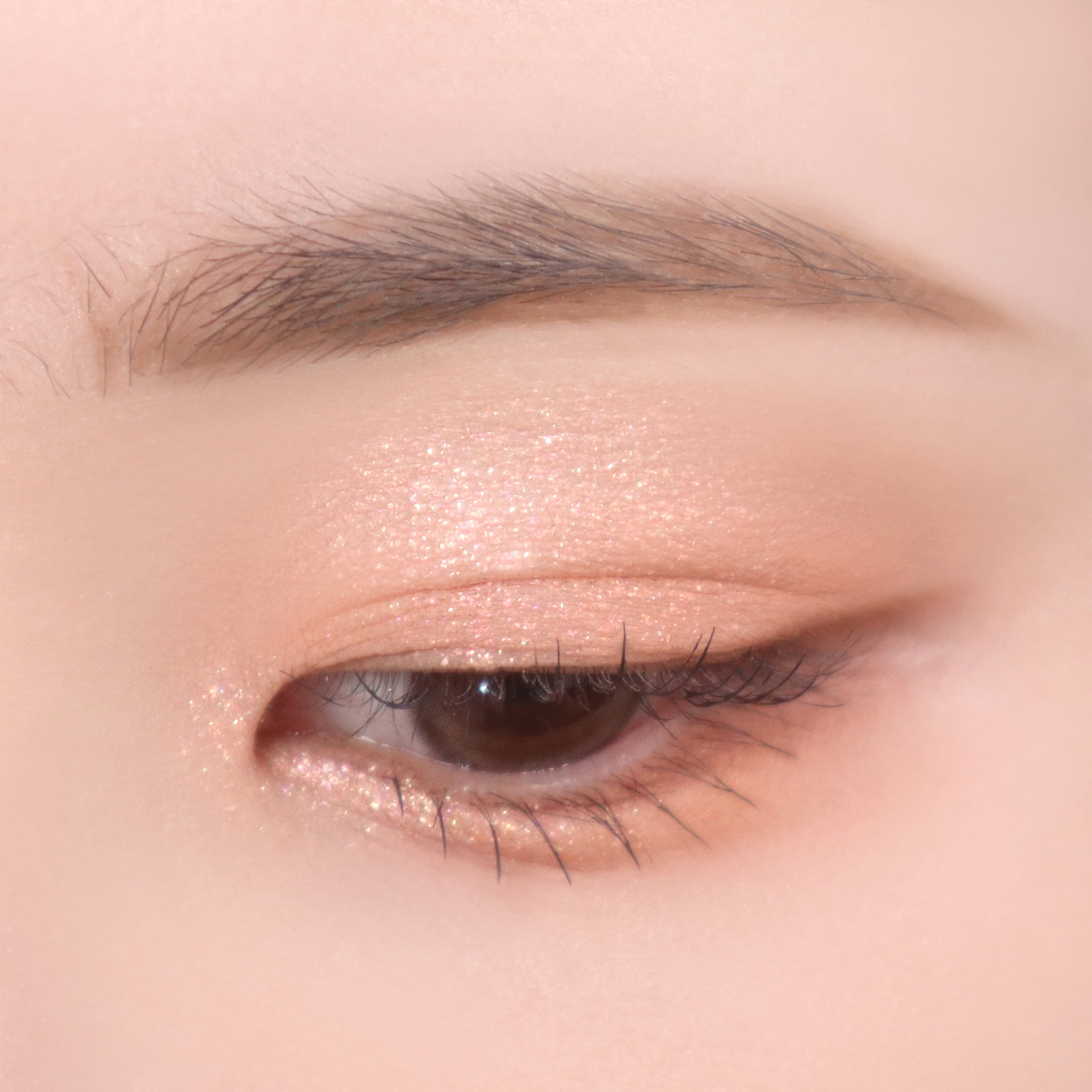 Auge mit Lidschatten in Nude-Tönen. Glitzer-Effekt auf dem Augenlid.