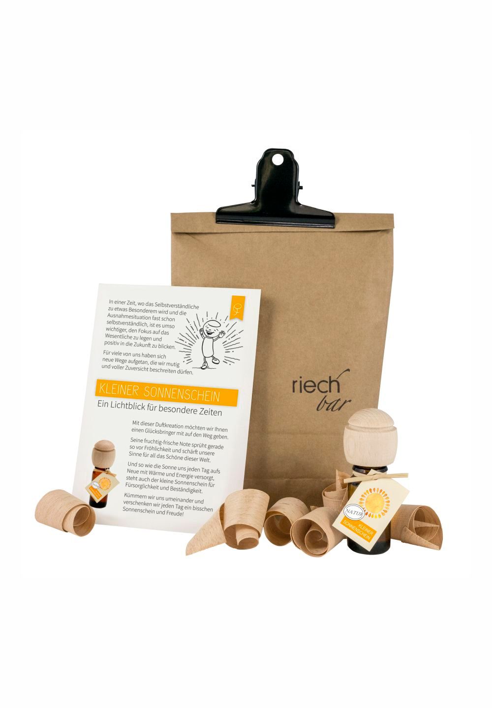 Produkt-Set mit Papiertüte, Holzfigur, Holzspänen und Flyer. Aufschrift: Kleiner Sonnenschein. Marke: riech bar.