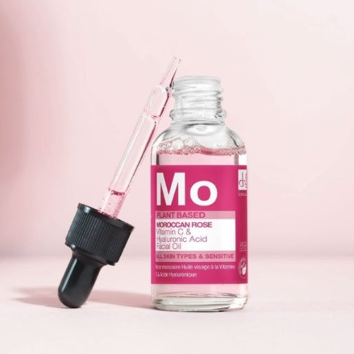 Gesichtsölflasche mit rosa Etikett und schwarzer Pipette. Aufschrift: Moroccan Rose, Vitamin C & Hyaluronsäure. Pipette ragt heraus. Klare Glasflasche.