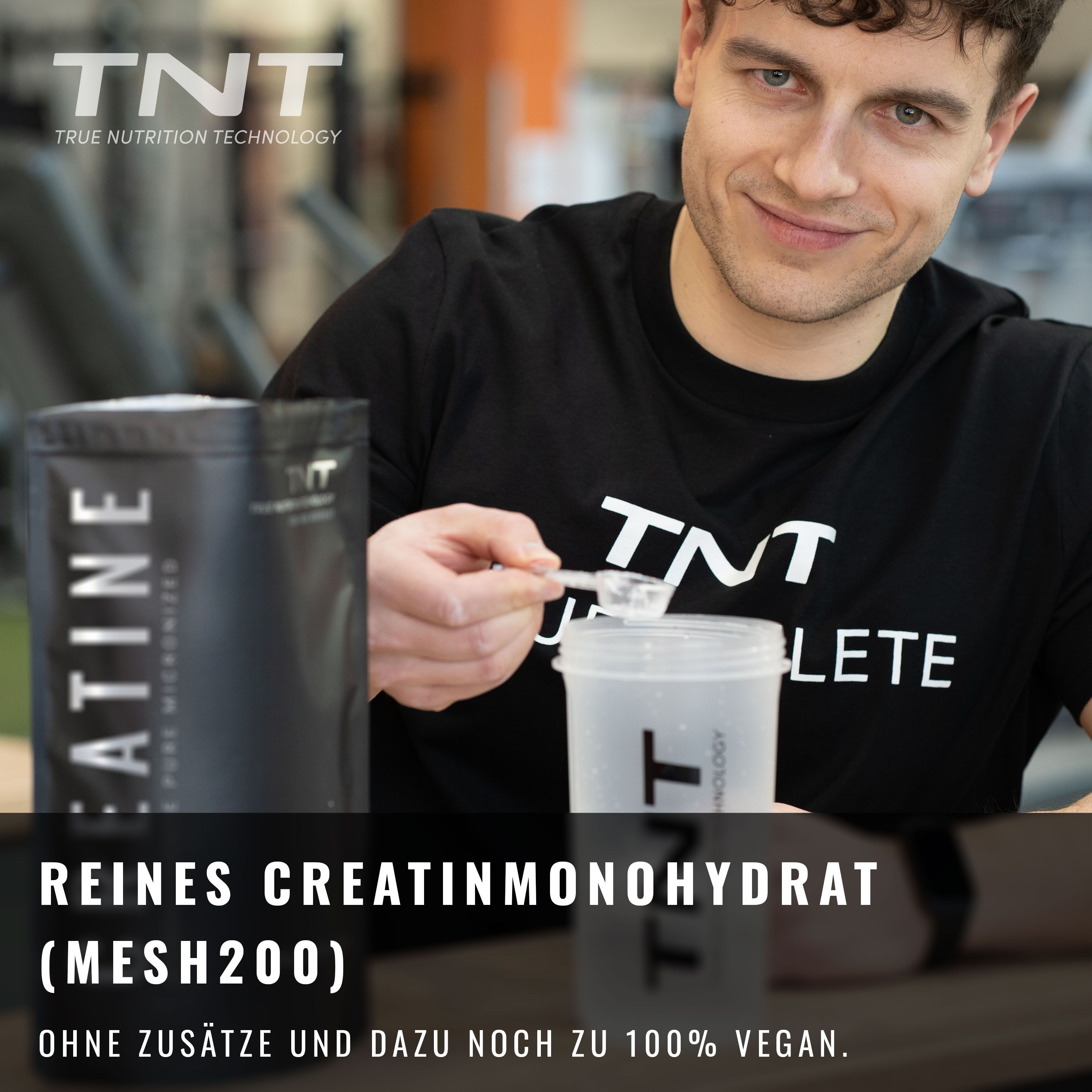 Mann hält Löffel über Becher. Neben ihm steht eine "TNT Creatine" Verpackung. Text: Reines Creatinmonohydrat (mesh200).