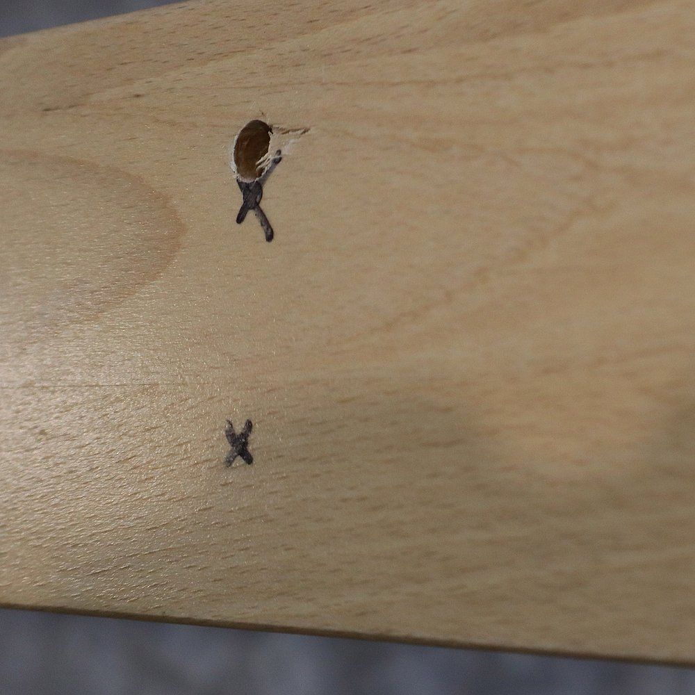 Detailansicht: Bohrlöcher und Markierungen auf dem Holz der Kletterwand.