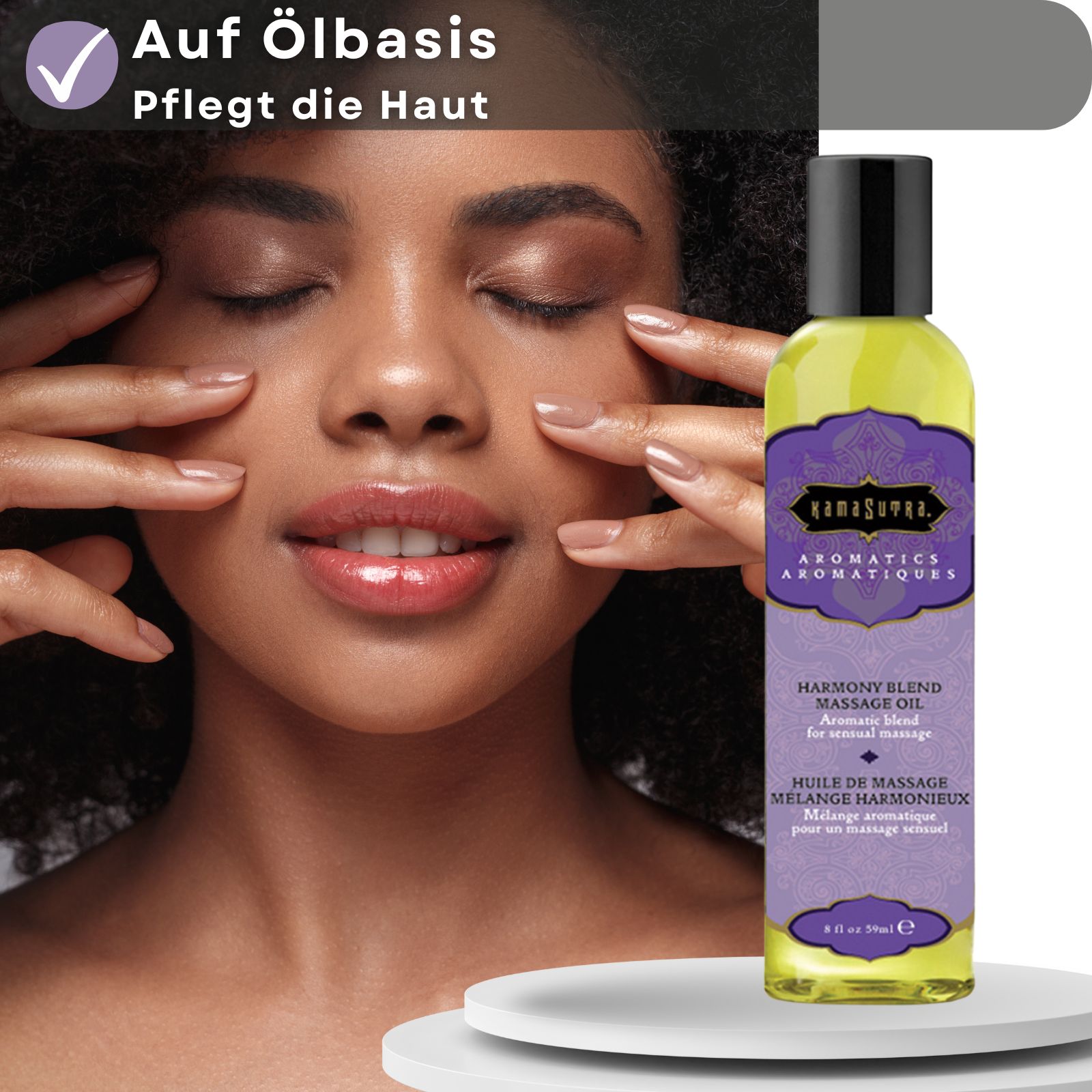 Flasche mit Massageöl. Lila Etikett mit Produktnamen und Text. Schwarzer Deckel. Auf Ölbais. Frau berührt Gesicht.
