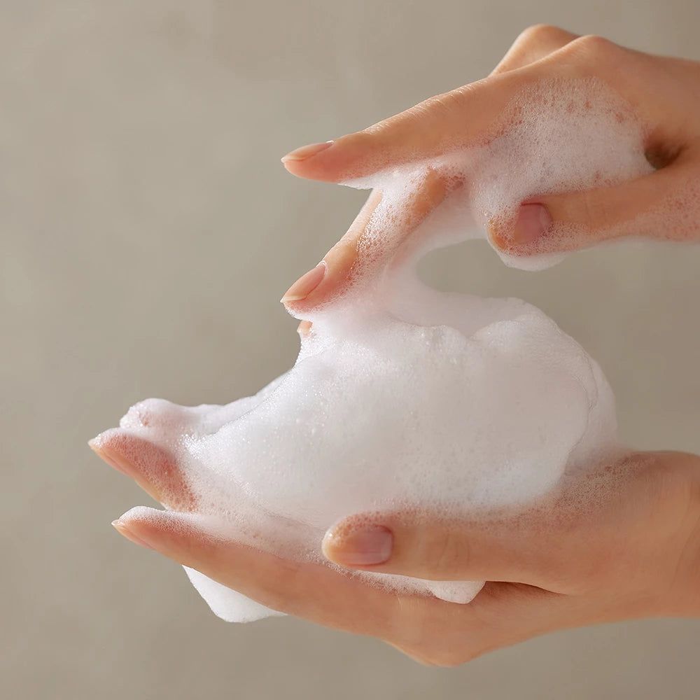 Hände mit Schaum. Der Schaum ist weiß und cremig.