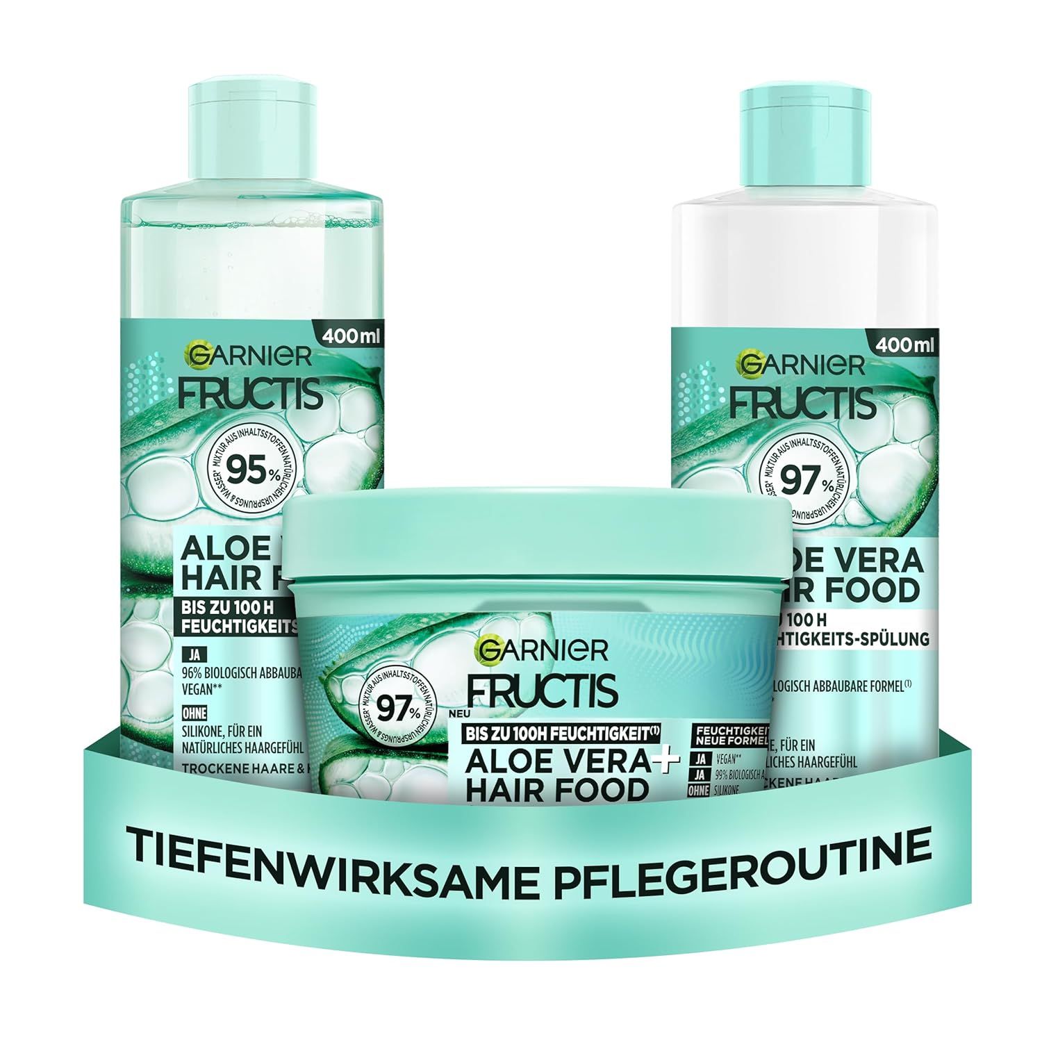 Drei Produkte der Garnier Fructis Aloe Vera Hair Food Serie: Shampoo, Spülung und Maske. Auf einer grünen Unterlage angeordnet.