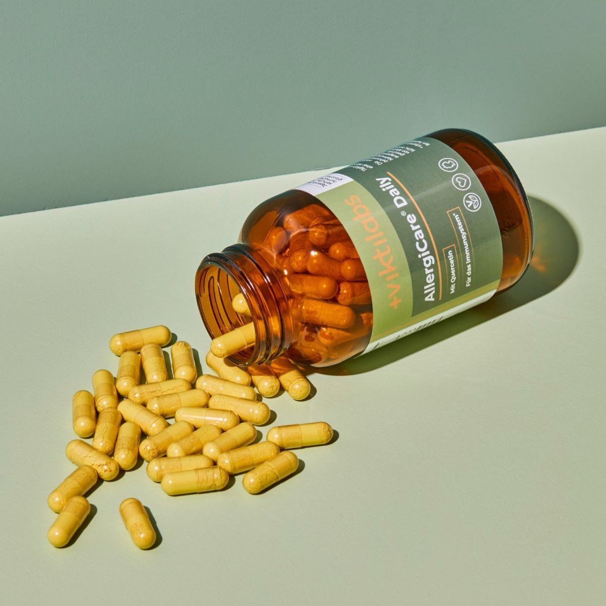Braune Glasflasche mit AllergiCare® Daily Kapseln, liegt. Kapseln sind herausgefallen. Aufschrift: Quercetin, Für das Immunsystem.