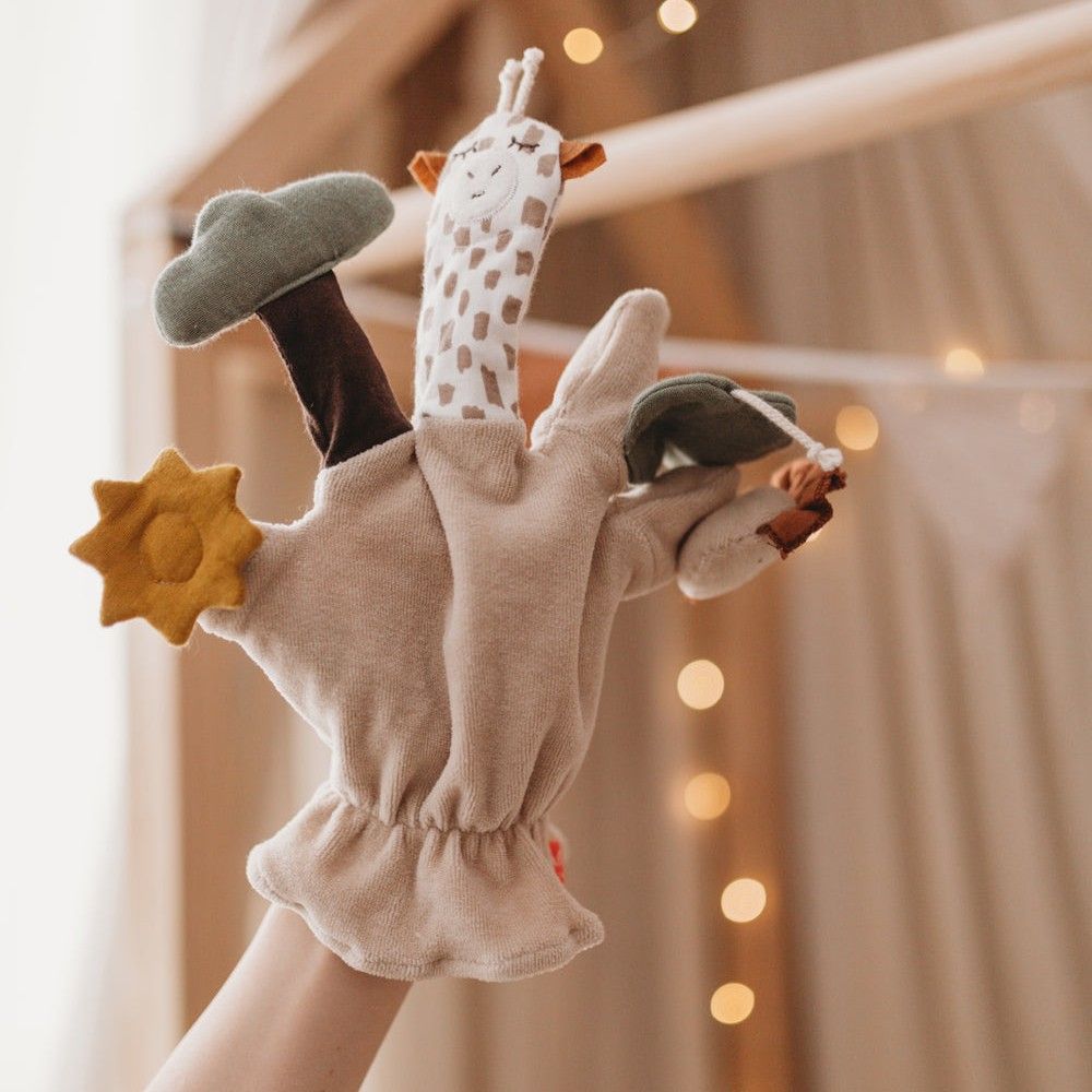 Fingerspielfigur Giraffe, beige, mit Giraffen-, Löwen- und Blattformen. Gelber Stern. Stoffhandschuh. Hand hält die Figur.