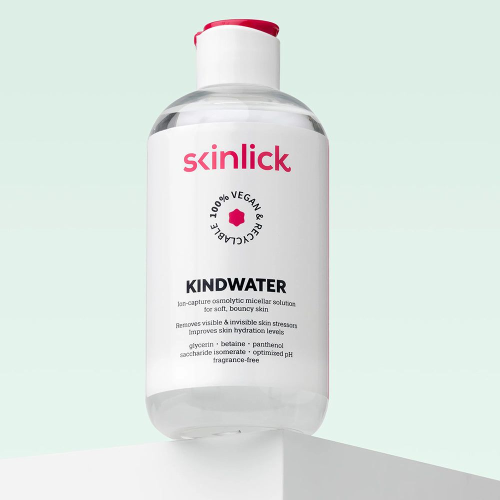 Flasche SKINLICK Kindwater Mizellenwasser auf einem Podest. Transparente Flüssigkeit.