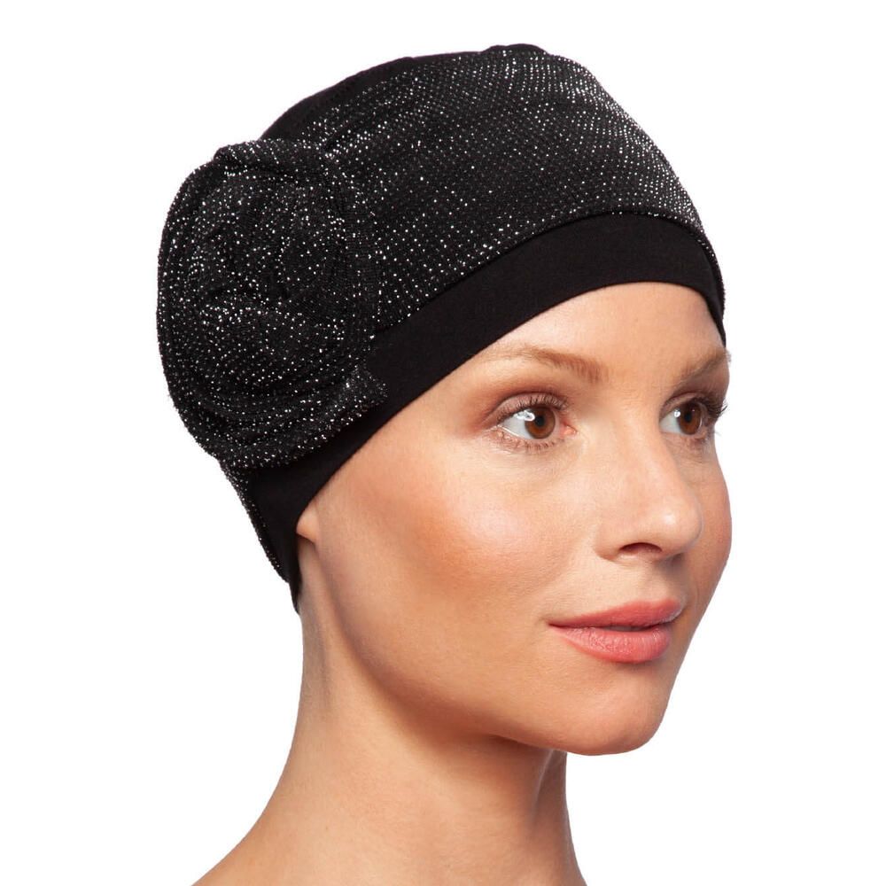 Schwarzer Turban mit glitzerndem Stoffteil und Blüte. Seitenansicht auf einer Frau.
