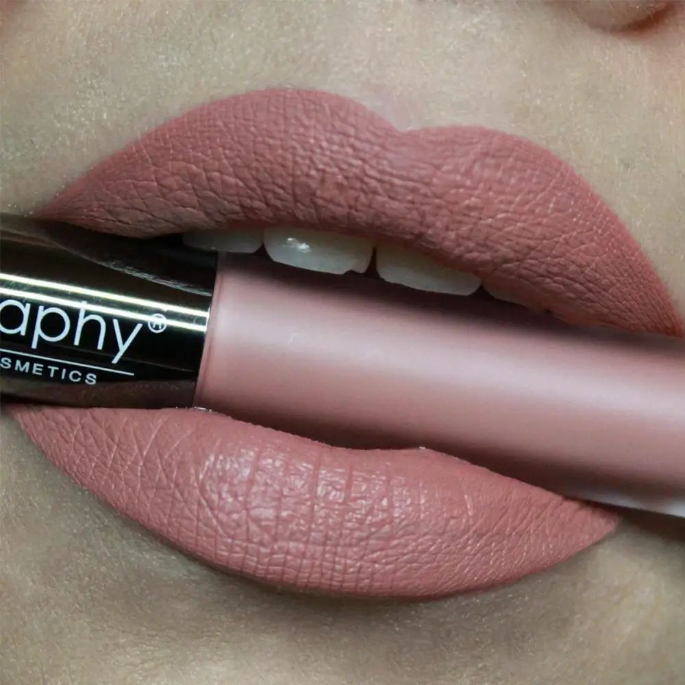 Mund mit aufgetragenem, rosabraunem Lippenstift. Lippenstiftflasche im Mund. Marke BODYOGRAPHY.