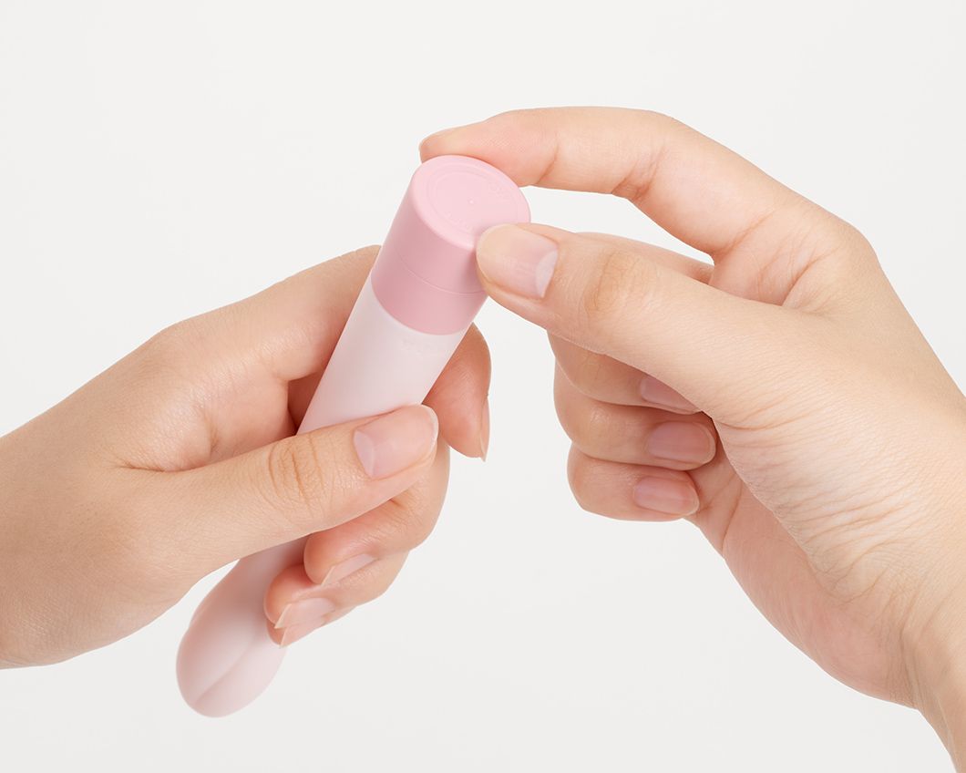 Rosa Vibrator, Basis wird von Händen geöffnet. Zylindrische Form.