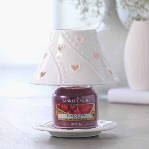 Kerze im Glas mit rotem Wachs, unter weißem Lampenschirm mit Herzmuster. Marke: Yankee Candle.