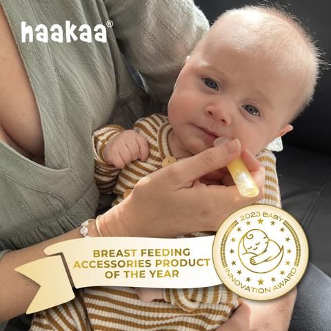 Ein Baby erhält Kolostrum aus einem Behälter. Ein goldenes Abzeichen zeigt "Breast Feeding Accessories Product of the Year".