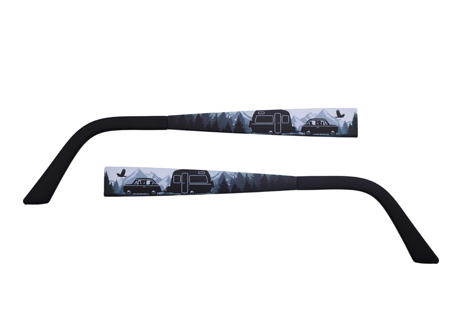 Zwei schwarze Brillenbügel mit Landschaftsmotiv. Motiv zeigt Auto, Wohnwagen und Berge. Schwarze Enden.